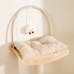Soft beige corduroy cushion on curved birch wooden shelf with hanging plush cloud toy on cat tree hammock