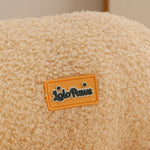 Close-up of beige bouclé fabric with orange Iglo Paws label on XL pet couch bed, part of a cat tower and scratcher combo for .