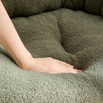 Close-up of hand pressing soft green bouclé fabric on an XL pet couch bed for cats and dogs