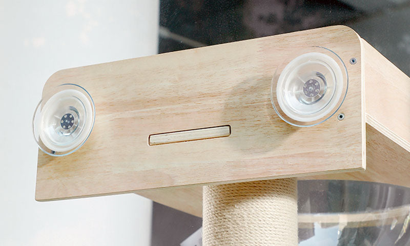 Light wooden cat perch with two clear suction cups attached to a smooth surface and a beige sisal post below